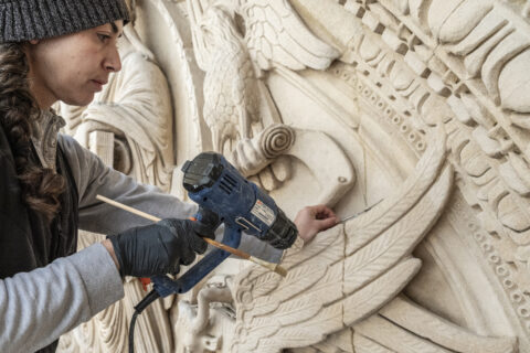 La restauratrice Alice Wasson de l'Atelier Bouvier intervenant sur le portail de l'église Saint-Trophime au cours de l'opération de dépoussiérage et de nettoyage 2025. Photo : Kaëlis Esteban Robert / Ville d'Arles.