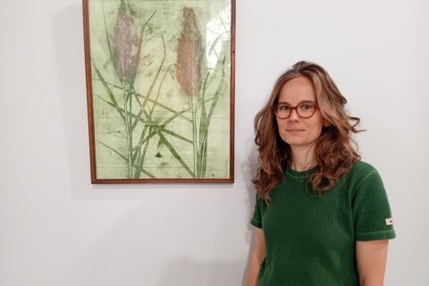 L'artiste Anne Perier devant l'une de ses oeuvres, lors de son exposition à la médiathèque d'Arles, intitulée "Voir à travers la roselière", durant les mois de septembre et d'octobre 2025. Photo : Ville d'Arles.